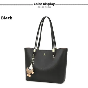 Detail of black pebbled tote bag featuring gold logo and cute monster plush charm