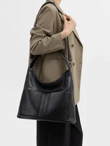 Detail of black tote bag featuring textured lychee pattern and hand-woven stitching