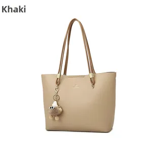 Detail of khaki tote bag with litchi grain leather and a cute brown monster pompom charm