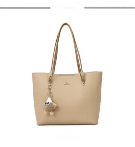 Close-up of khaki tote bag in pebble leather with delicate logo and plush doll charm
