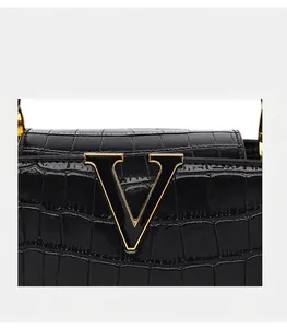 Détail du cuir noir embossé crocodile avec une grande boucle décorative en métal doré en V