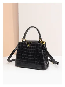 Détail du sac à main noir texture crocodile avec logo V doré et bandoulière réglable