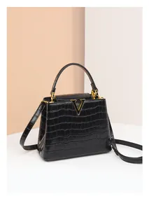 Détail du sac à main en cuir crocodile noir avec boucle métallique dorée en forme de V