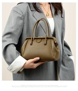 Detailed view of dark olive green leather handbag with lychee texture and round handles