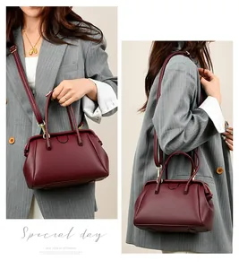 Detail of burgundy lychee grain leather handbag with gold-tone hardware and top handles