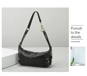 Macro detail of black quilted crescent moon shoulder bag with golden hardware accents