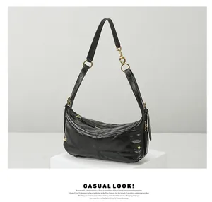 Close-up of black quilted leather shoulder bag with gold hardware and zipper detail