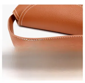 Detailed view of brown litchi leather handle with contrasting white stitching for handbag