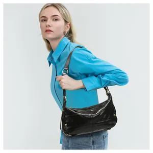 Detail of black quilted shoulder bag with glossy leather finish and gold zipper