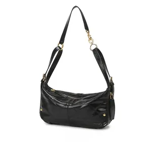 Detail view of quilted black crossbody bag with shiny finish and gold ring hardware