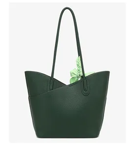 Close-up of deep green tote bag featuring lychee grain leather and silk scarf detail