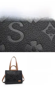 Detailed macro view of black embossed leather tote featuring soft waterproof texture and metal logo