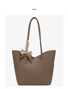 Detailed macro view of khaki tote bag featuring lychee grain leather and plaid scarf knot