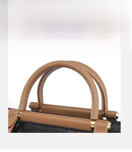 Detail of round brown handle and gold metal hardware on black textured leather tote bag