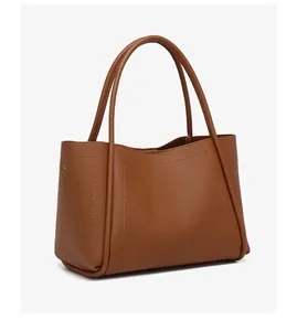 Detail van de bruine lychee leer tote tas met structuur en metalen klinknagels aan de zijkant