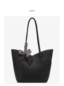 Close-up of black tote bag featuring premium lychee grain leather and plaid bow detail
