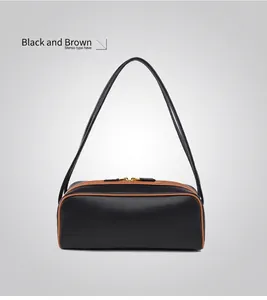 Detalle de bolso de hombro minimalista negro con borde marrón y cremallera de color dorado