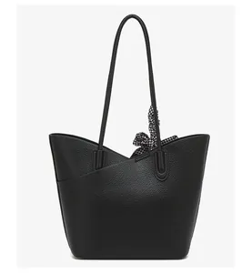 Detail of black lychee-grain tote bag featuring a chic houndstooth silk scarf handle