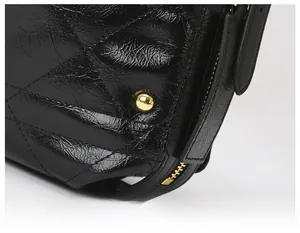Close-up of black quilted leather shoulder bag with golden rivets and metal zipper details