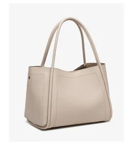 Close-up van de beige korrelige leerstructuur en metalen klinknagel op de tote tas