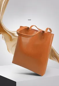 Detailed close-up of brown oiled leather tote bag with vintage texture and golden satin