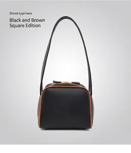 Detalle del bolso de hombro cuadrado negro con bordes marrones y cremallera dorada
