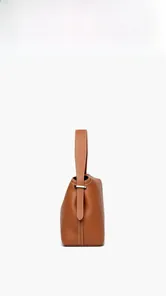 Detail of brown litchi pattern leather handbag with white contrast stitching and metal ring