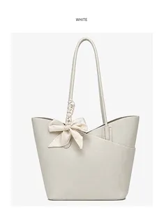 Close-up of white tote bag with lychee grain texture and elegant bow charm detail