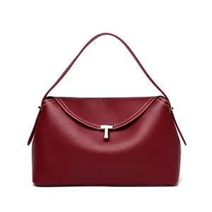 Detail of dark red textured leather handbag with silver T-lock and white stitching