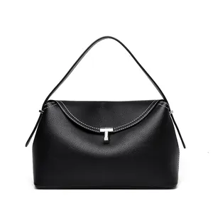 Detail of black pebbled leather texture with white stitching and silver T-lock on handbag