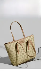 Vista detallada del bolso tote grande en lona beige con patrón M y asas de cuero marrón