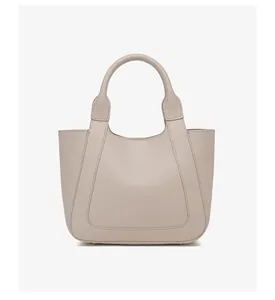 Gedetailleerde opname van beige emmer tas met litchi-textuur en decoratieve naden