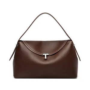 Detail of dark brown pebble leather bag featuring contrast stitching and T-shaped metal clasp