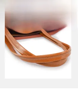 Detailed macro view of litchi textured leather handles on a brown tote bag