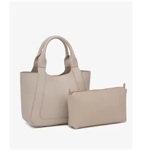Detail van de minimalistische beige emmertas en bijpassende pouch met leertextuur