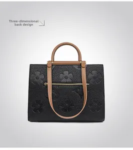 Detail of floral embossed leather handbag back view with functional metal zipper pocket