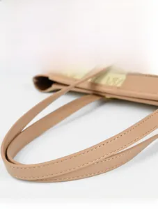 Detalle de asas beige y costura doble de precisión en el bolso tote para mujer