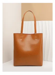 Detailed view of the brown oil wax leather texture and stitching on the tote bag