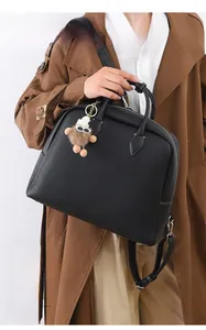 Dettaglio della borsa tote in pelle nera a grana con ciondolo a forma di orsetto bruno