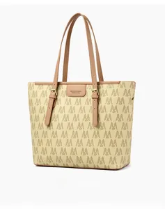 Detalle del bolso tote de lona con monograma, asas de cuero marrón y hebilla de metal dorado