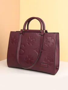 Deep burgundy tote bag with embossed floral patterns and dual shoulder straps