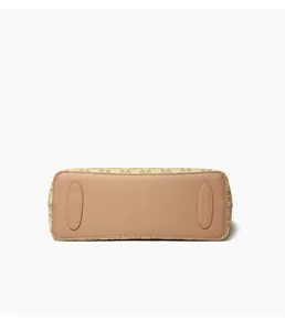 Detalle de la parte inferior del bolso tote con patrón de monograma beige y base de cuero rosa