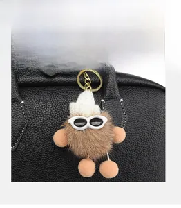 Dettaglio di un portachiavi creativo in ecopelliccia marrone con occhiali su borsa nera