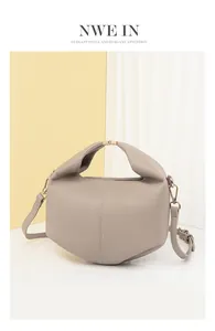 Detail of taupe leather crossbody bag with golden buckles and textured finish