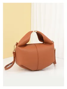 Close-up of brown litchi grain leather handbag with golden buckle and sleek stitching