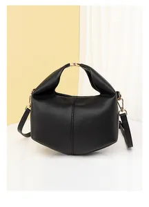 Close-up of black lychee-grain leather texture and golden metal buckle on crossbody bag