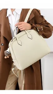Dettaglio borsa tote beige in pelle martellata con ciondolo di peluche e tracolla