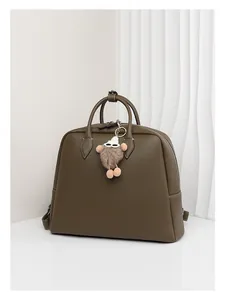 Dettaglio borsa a mano in pelle martellata verde oliva con ciondolo mostro di peluche