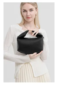Detail of black lychee grain leather handbag with gold metal hardware and folded design