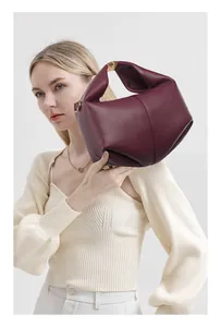 Detail of burgundy lychee grain leather fold design with golden metal buckle handle
